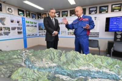 朝田所長（右）からジオラマを使って、八ツ場ダムの役割や特徴、周辺の地形などの説明を受ける大澤知事の写真